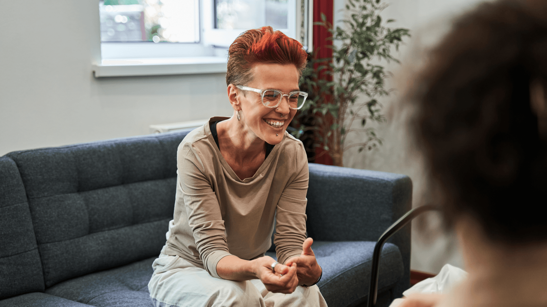 A woman sitting on a couch in therpist office, smiling