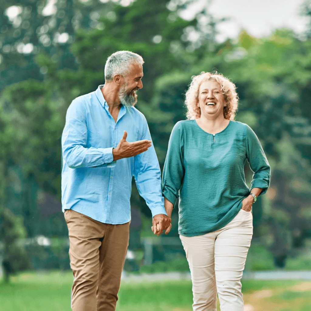 middle aged couple, walking in park, holding handas and laughing