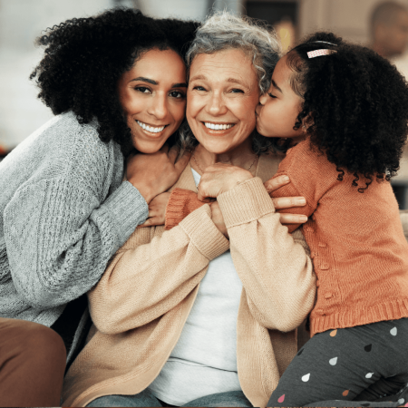 ther generations, grandmother, daughter and granddaughter, cuddling and smiling