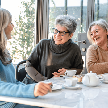 three middleagaged woman having coffee and laughing