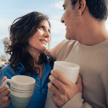 husband and wife embraving with a cup of coffee looking into each others eyes