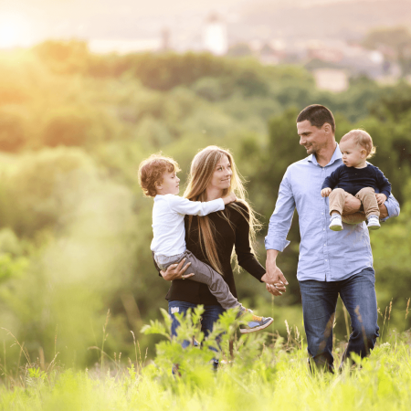 Young happy family walking in field on a summers day