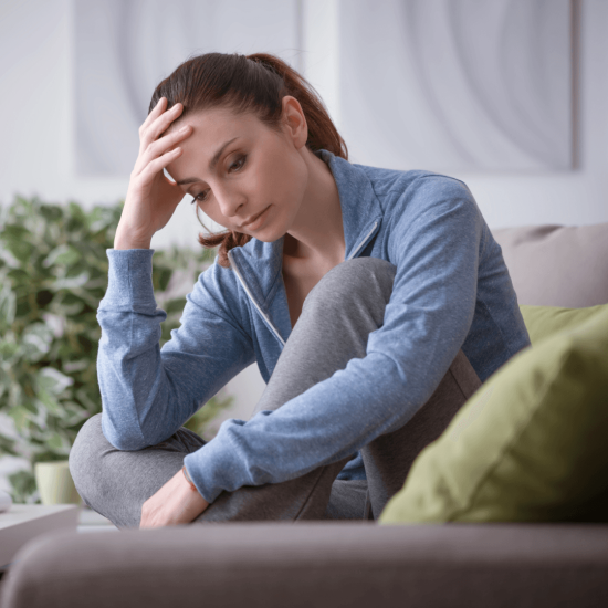 Woman sitting on a couch with head in hand, overwhelmed